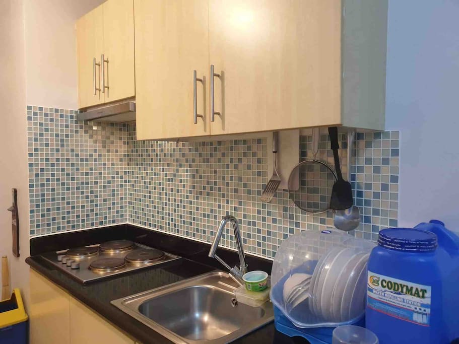 Kitchen area, electric stove with exhaust, microwave and refrigerator, rice cooker, pots and pans