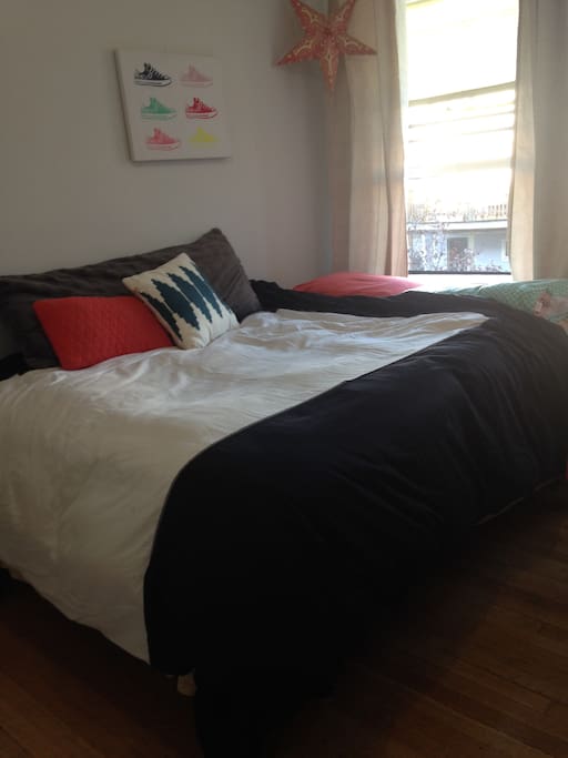Queen bed with a body pillow and throw pillows
