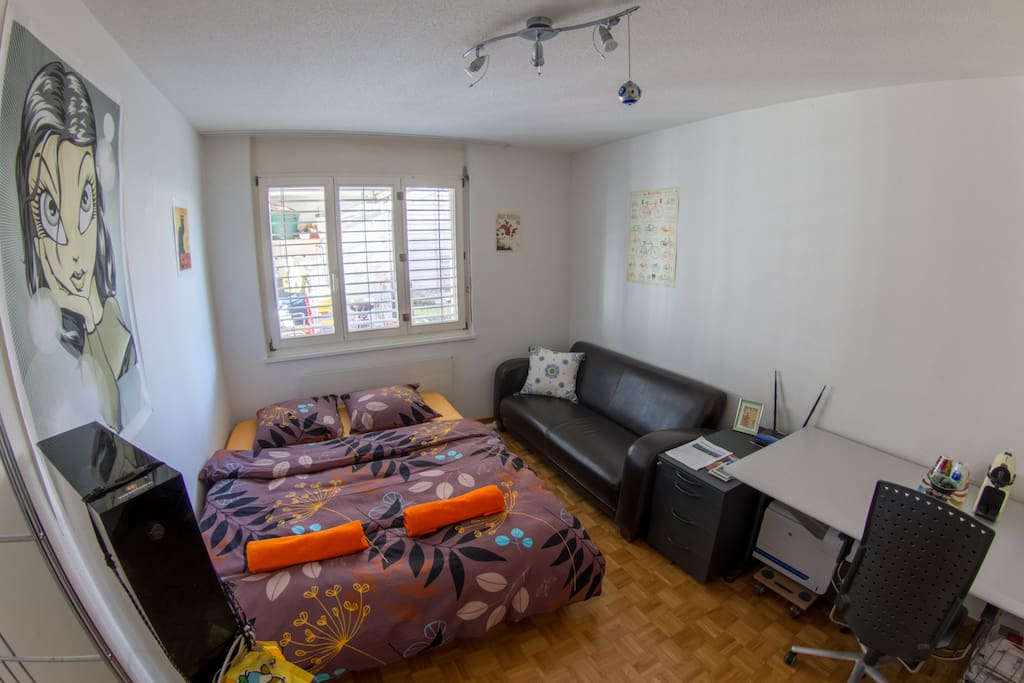 Guestroom with double bed, desk and couch