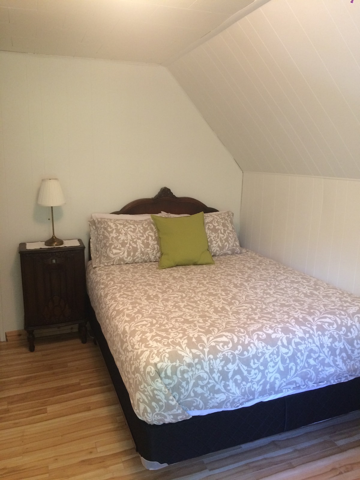 חדר לופין. מיטת קווין עם ראש מיטה עתיק, רדיו ישן כשולחן צד ושידה עתיקה.