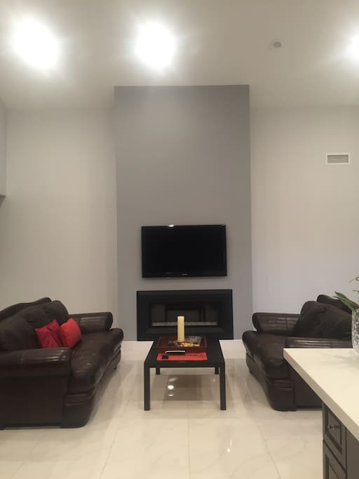 High ceiling living area with large flat screen TV and remote controlled gas fireplace