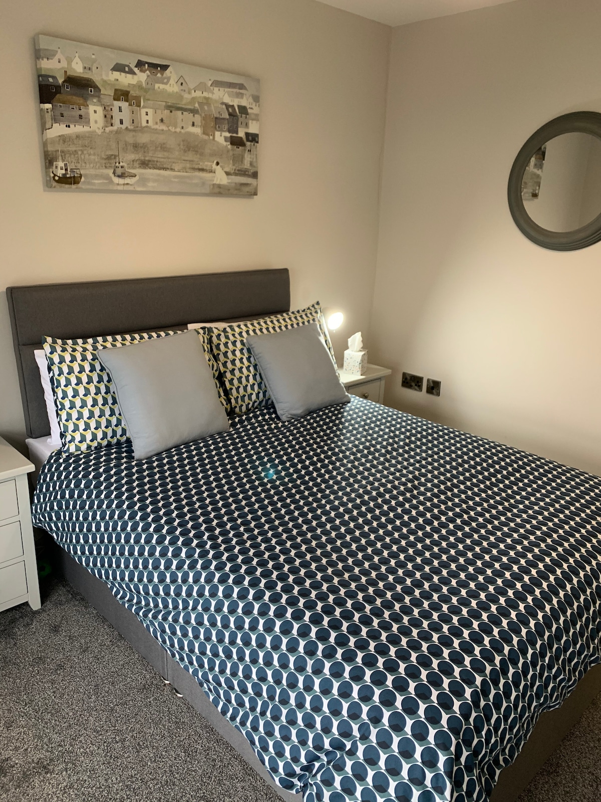 تحتوي غرفة النوم الأولى في الطابق السفلي على سرير مزدوج وخزانة ملابس وطاولتين بجانب السرير.