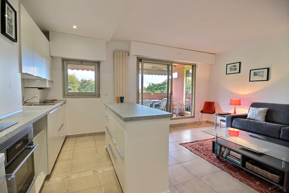 Veľká obývacia izba s výhľadom na terasu s obývacou izbou, veľkou TV obrazovkou, otvorenou kuchyňou a vnútorným a vonkajším jedálenským priestorom.