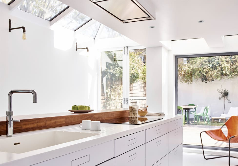 Large open-plan kitchen equipped with Miele traditional & steam ovens, dishwasher, Quoker tap, Conrian worktop, a long breakfast bar & 6 high stools opening onto the back garden