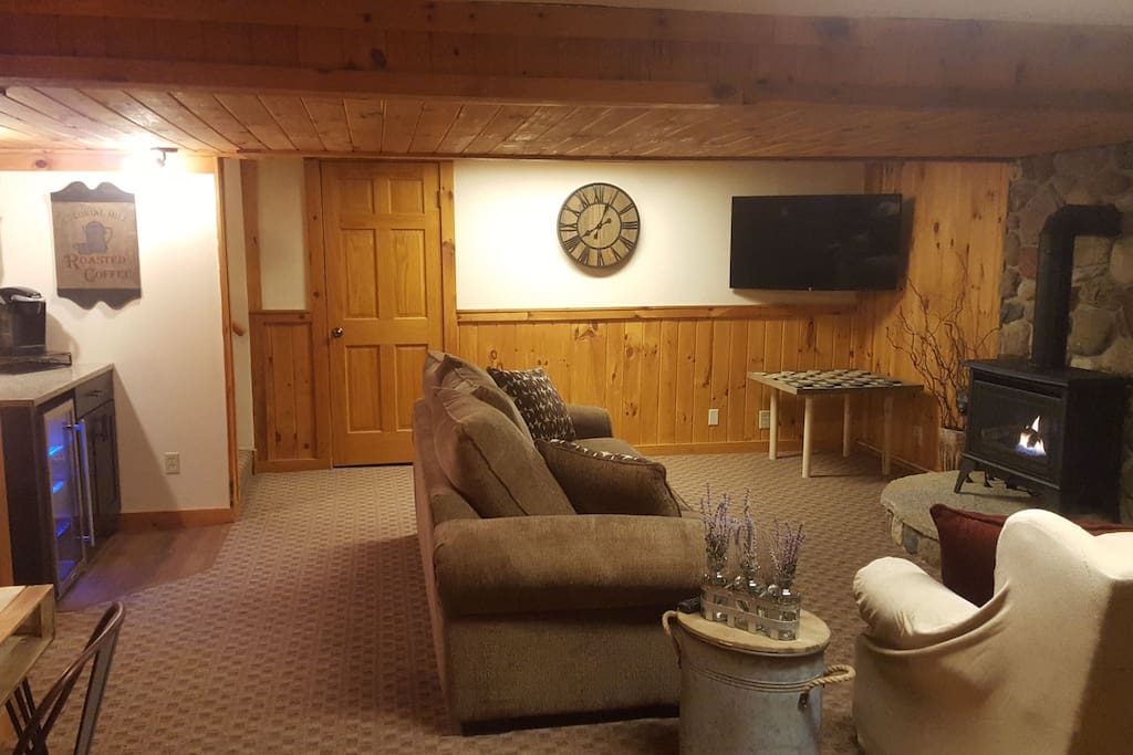 Living area - tv, coffee bar with beverage cooler, desk and gas wood stove. privacy door at the top of stairwell. Bluetooth speaker on desk.