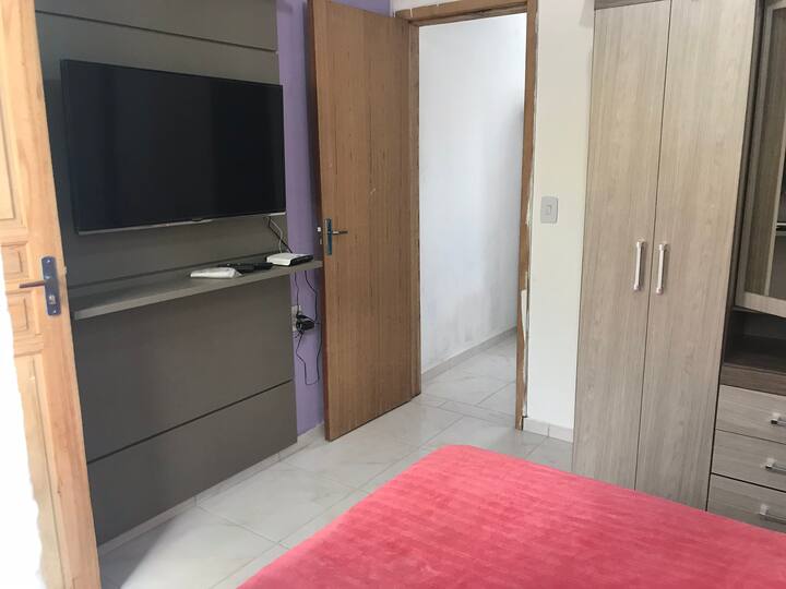 Dormitorio: TV , armario , cama, aire acondicionado y el pasillo del baño y la sala de estar/cocina.