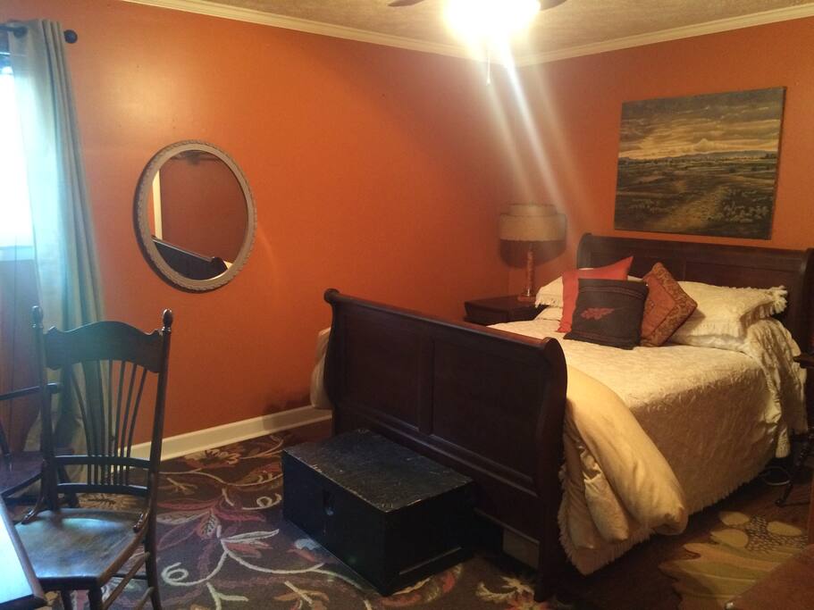 The orange room features a Queen bed, closet, dresser, and a tv on the wall.