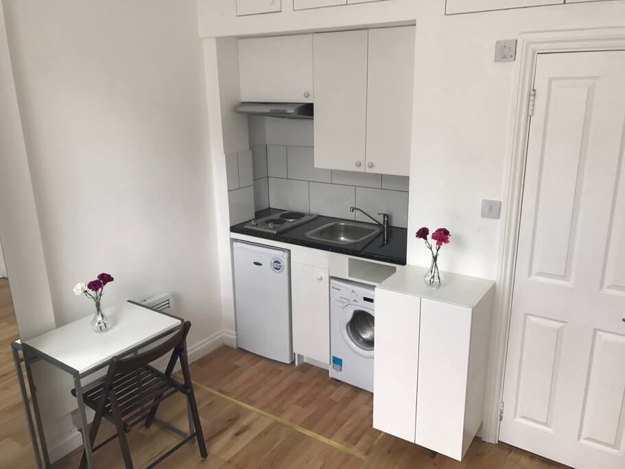 Kitchen with washing machine, fridge and the bathroom door