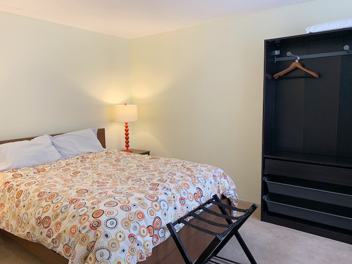 El dormitorio principal es luminoso y cómodo con una cama tamaño queen. Armoire ofrece almacenamiento y espacio para colgar la ropa. 
