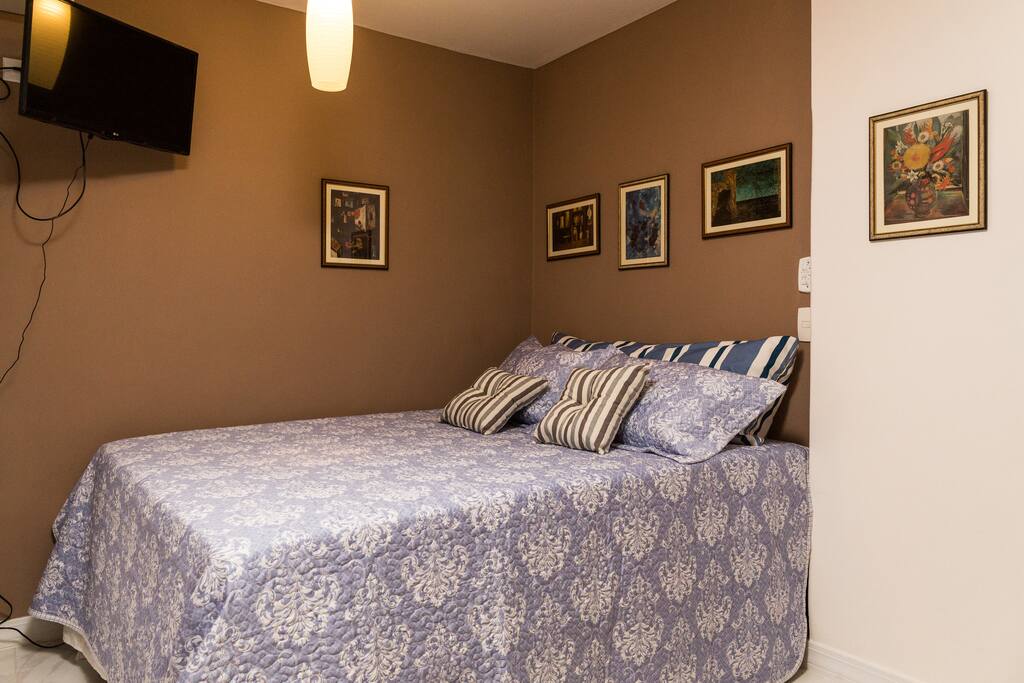 Cama queen size com roupa de cama de excelente qualidade e bom gosto.