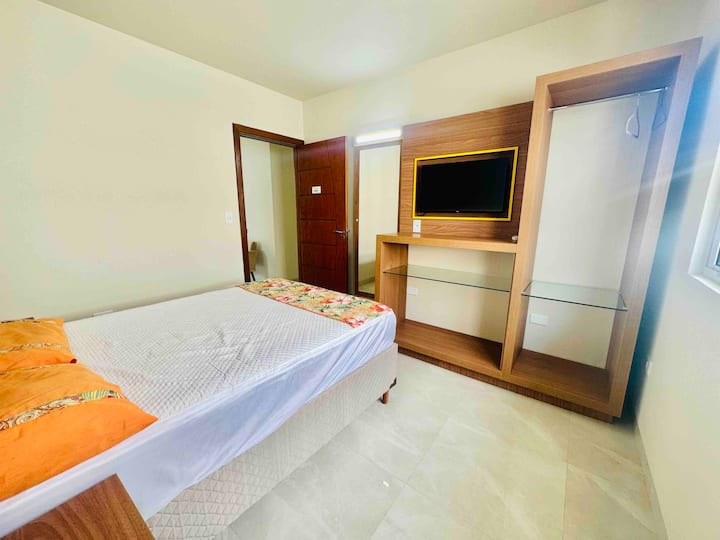 Spálňa/apartmán 3 s 1 manželskou posteľou, skrinkami, televízorom, klimatizáciou a veľkým zrkadlom na stene.