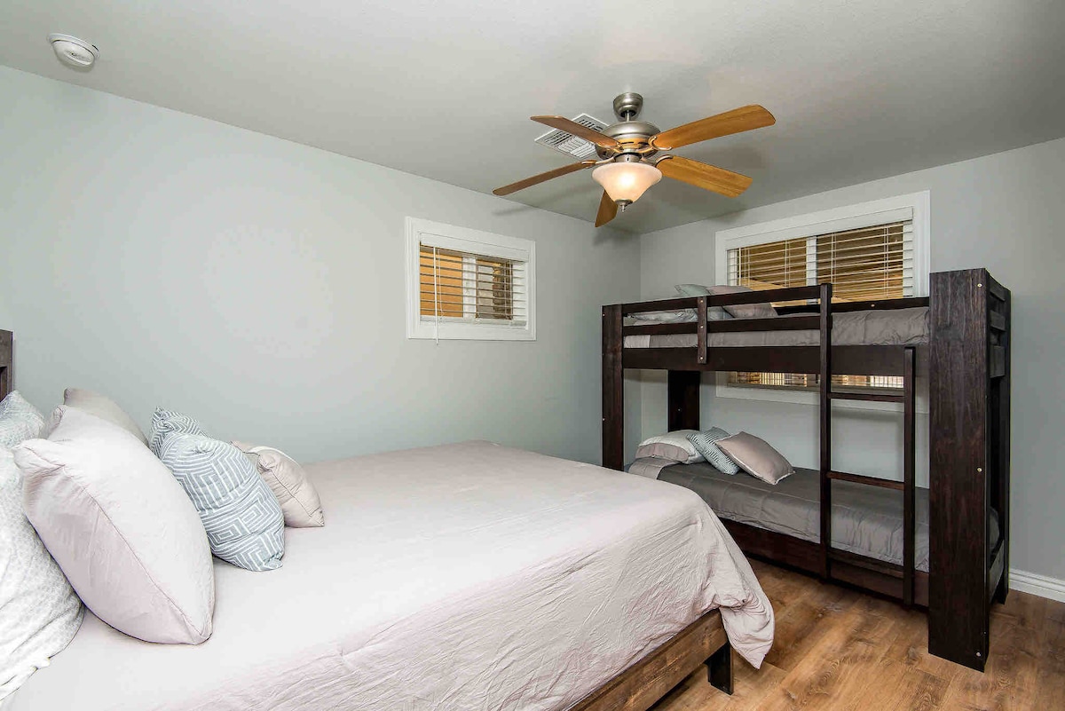 Dormitorio en el nivel principal con una cama tamaño queen y dos camas individuales sobre una litera doble.