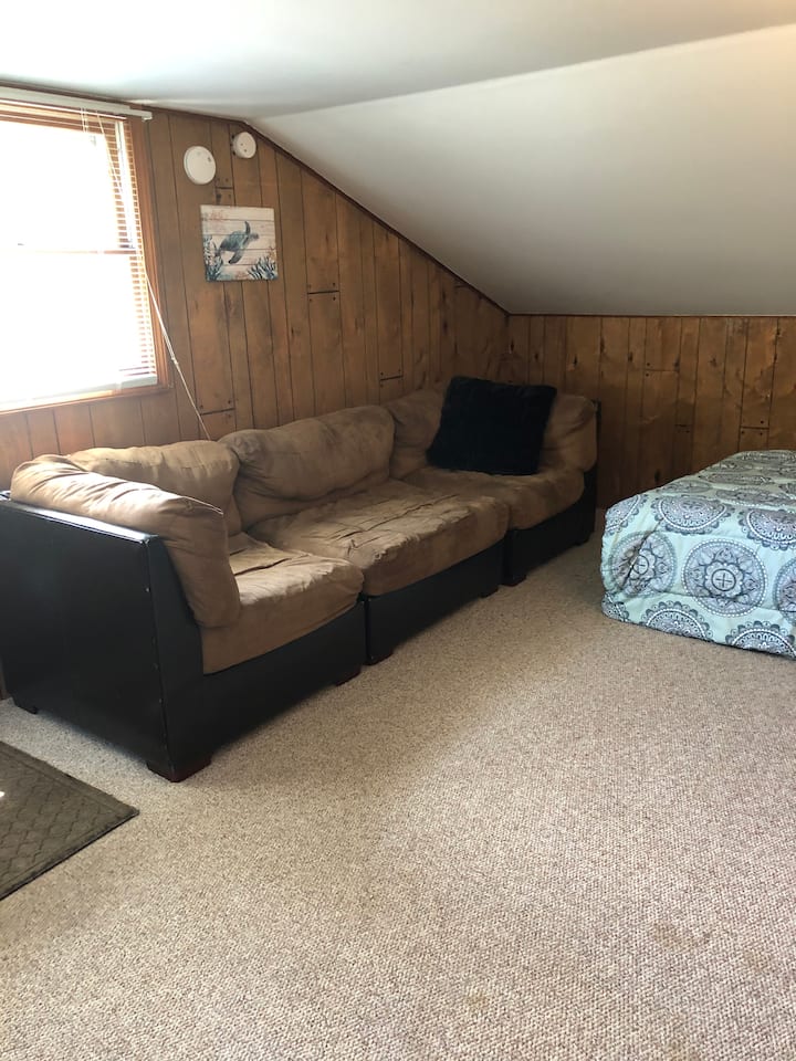 沙发可以多睡一人。沙发一侧有一张额外的被子，还有床单、毛毯和更多枕头。