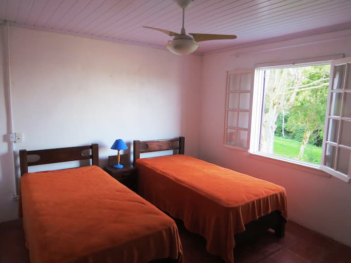 חדר שינה בקומה העליונה עם שתי מיטות יחיד, מאוורר תקרה, חדר אמבטיה במסדרון.