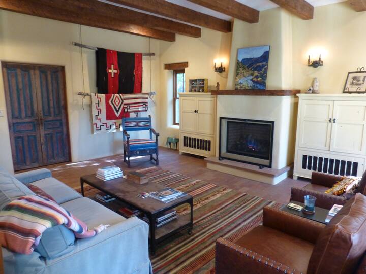 the great room features comfy leather chairs, a gas fireplace, antique doors to the guest wing and vintage native-american rugs