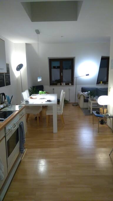 Im Wohnzimmer befindet sich eine offene Küche, ein sehr großer Esstisch und L-förmig abgesetzt eine Couchecke.