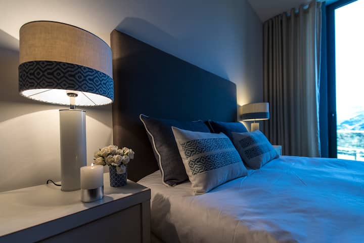Quarto azul e branco com cama de casal.