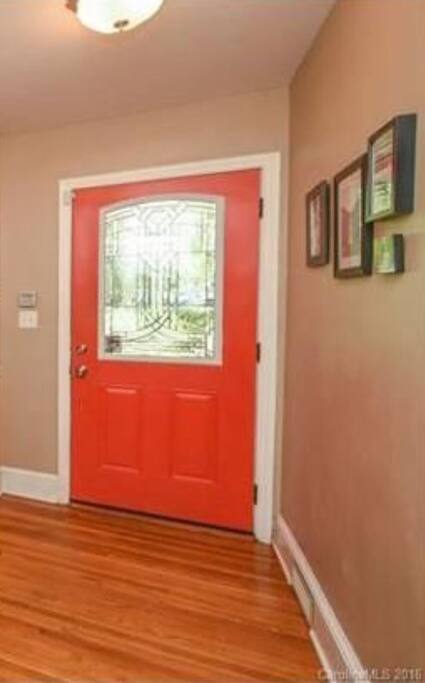 Red orange door with hallway leads to living room.