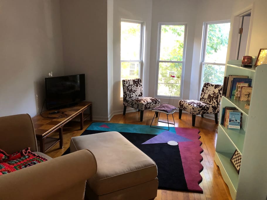 View of the living room seating area and the bay window overlooking the street.
