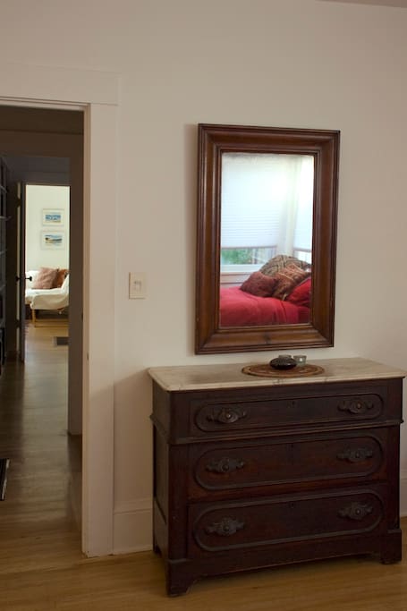 View south from master bedroom, bed reflected in mirror, living room in the distance