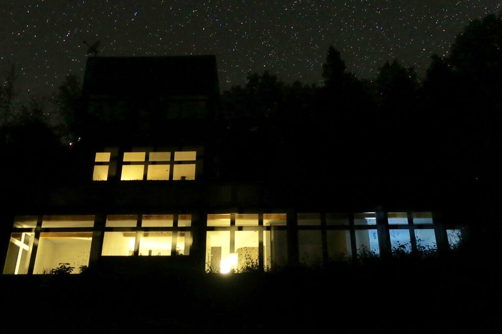 La maison vue de soir sous une nuit étoilée. / The house seen at night under the stars.