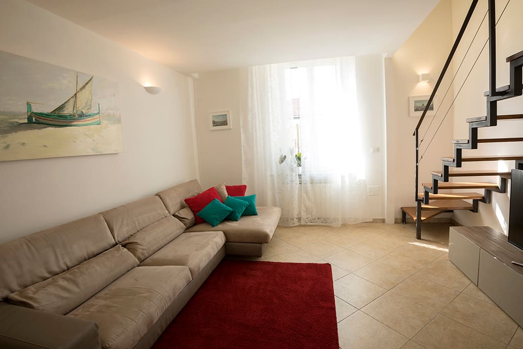 Un ampio e luminoso salotto con una scala per accedere alla zona notte/ ample and bright living room with a comfortable staircase to access the night zone