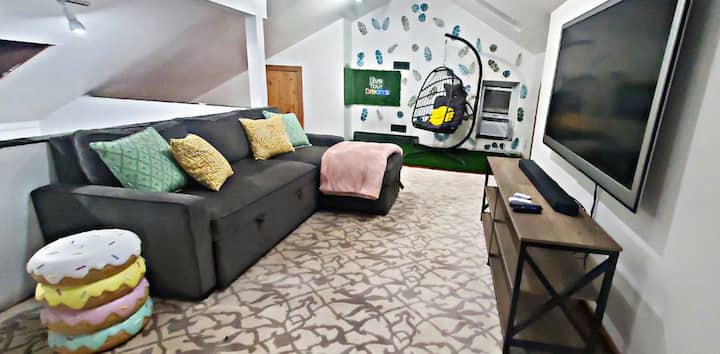 Një zonë argëtuese dhe ftuese e Loftit, me mur të përshtatshëm për fotografi në instagram.  Ky loft i rehatshëm përfshin një divan pop-up për organizime shtesë të fjetjes (fjetje 2) dhe ambientin dytësor të dhomës së ndenjjes. Përfshin gjithashtu një hapësirë pune shtesë.