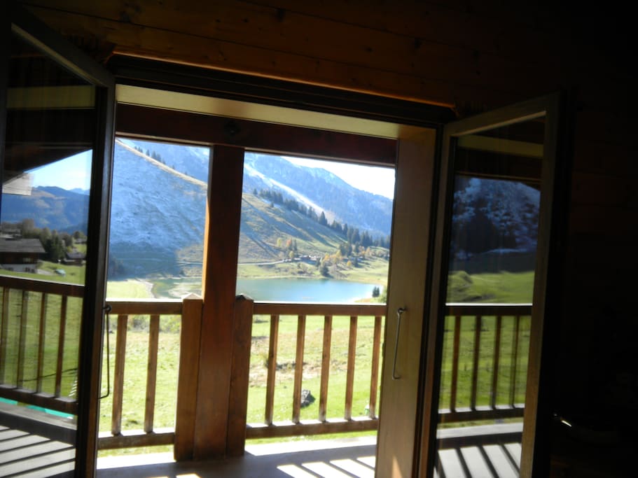 Le balcon avec table à manger offrant une vue sur le lac des Confins, en été