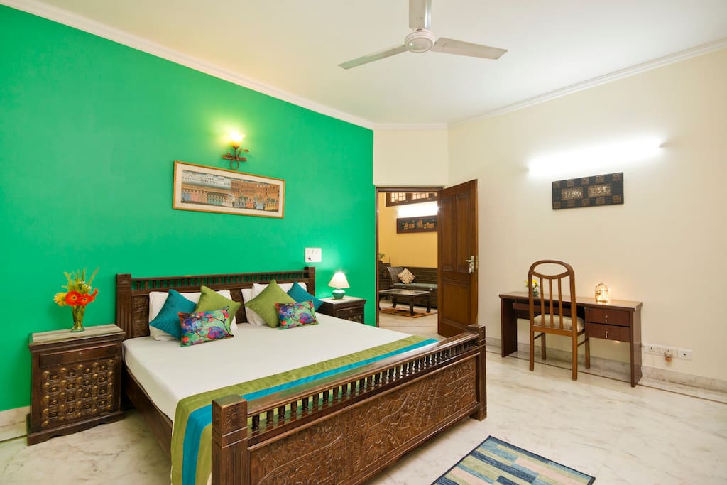 Relaxing rainforest green colored large master bedroom with the walk in closet and dresser apart from the attached washroom