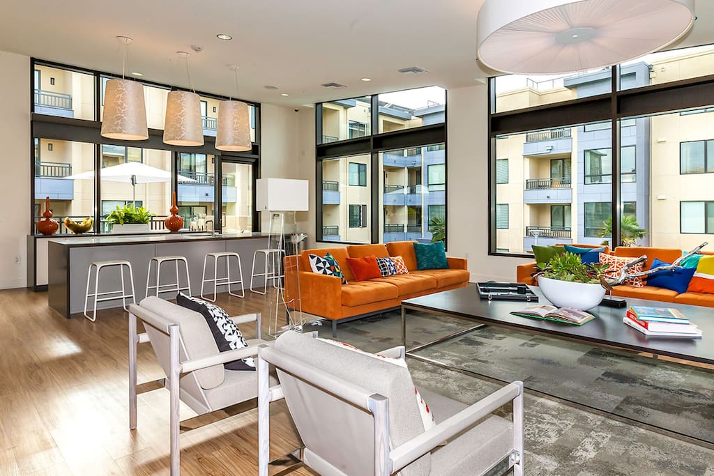 Clubhouse with large flat screen television, 3 smaller television, a fireplace, a kitchen area, and an outside patio with a barbecue.
