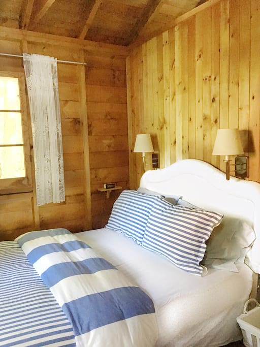 Bedroom #1 in the main cottage. Cozy double bed in corner room with 2 windows overlooking the forest.