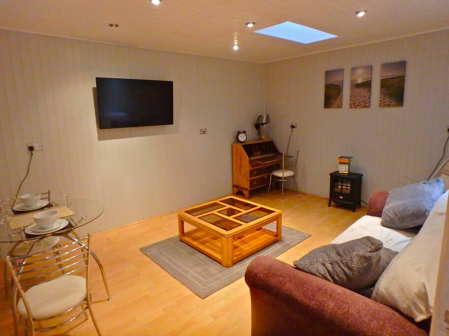 Living/Dining room with Smart TV, antique writing desk, rocking chair next to heater and dining table and chairs