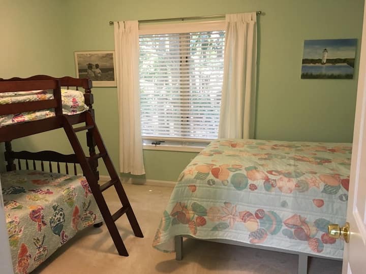 Vue sur la chambre au deuxième étage avec un lit complet et 2 lits jumeaux.