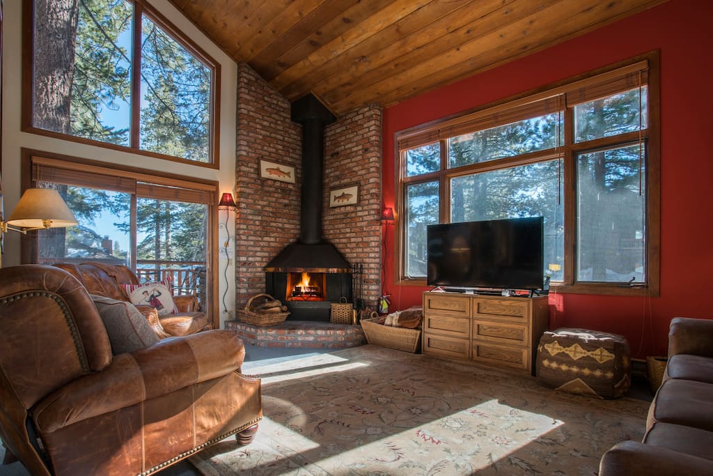 Large living area with high ceilings, grand windows, warm fire, and lovely patio