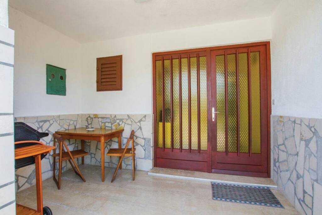 Covered terrace with small desk, chairs and barbecue