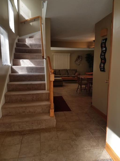 Front foyer leading to living area and kitchen ahead, downstairs bath with tub to right, and stairs leading up to the 2nd and 3rd floors. Also stairs to basement with full sized Washer/Dryer.