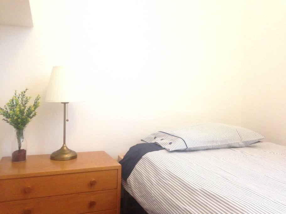 Habitación. Detalle de la cama, mesilla de noche y lámpara