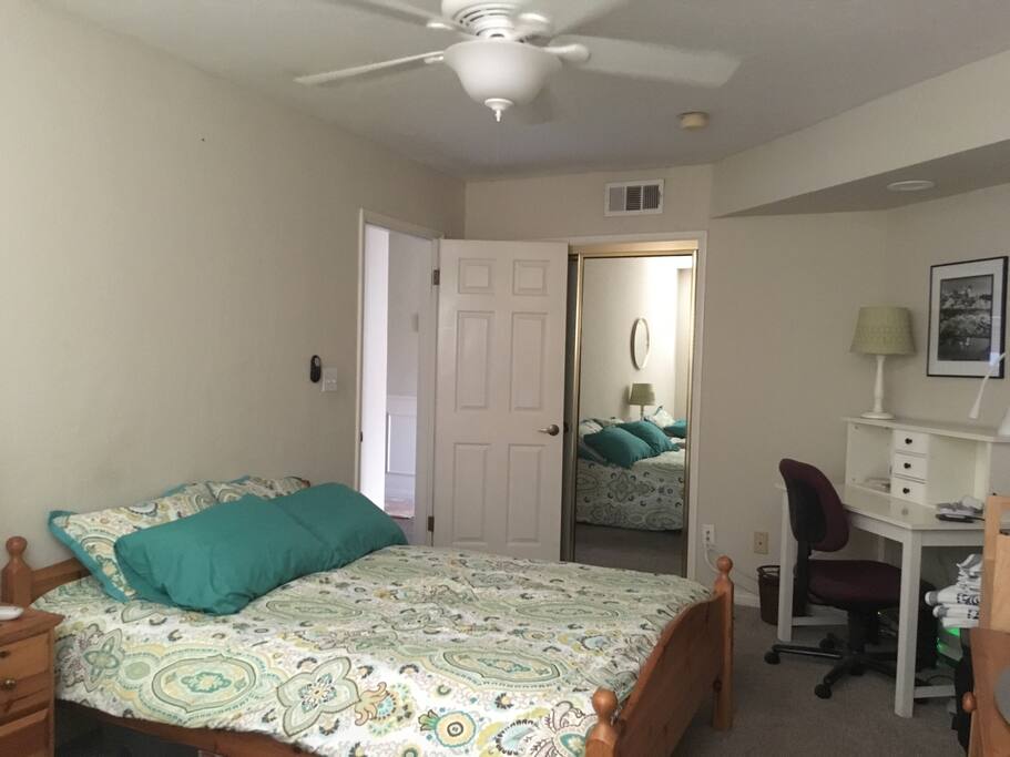 This spacious bedroom has a dresser, closet, remote control ceiling fan & light, TV and desk.