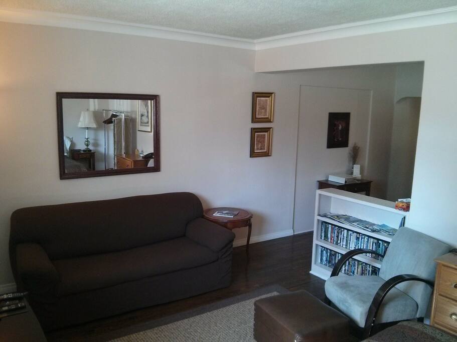 Combination Livingroom/Bedroom area with sofabed, chair and ottoman, mirror, travel brochures and maps, and telephone directories.