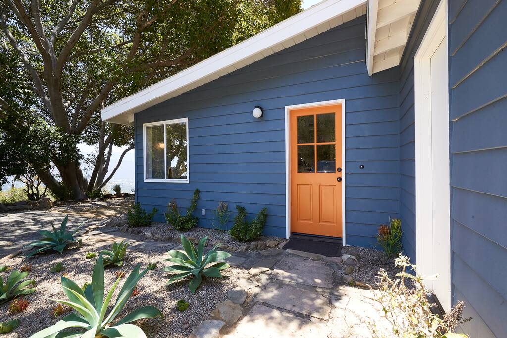 Side entrance from the carport has a cheerful orange door!