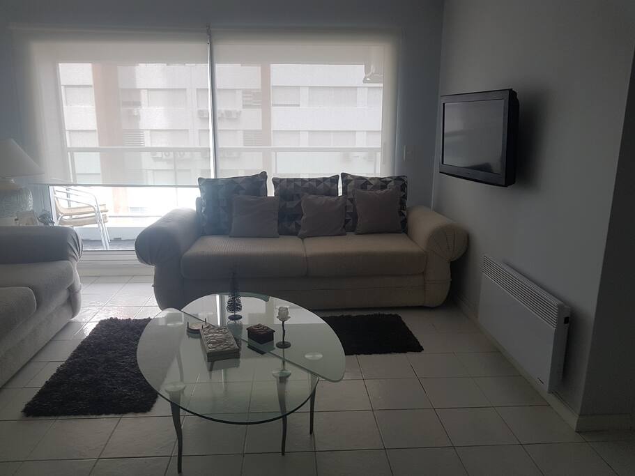 Mesa de cristal, con dos sillones y televisor.
