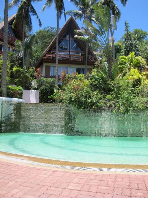 View from the deck to the pool and waterfall and beyond to the house, the actual studio is obscured by greenery.
