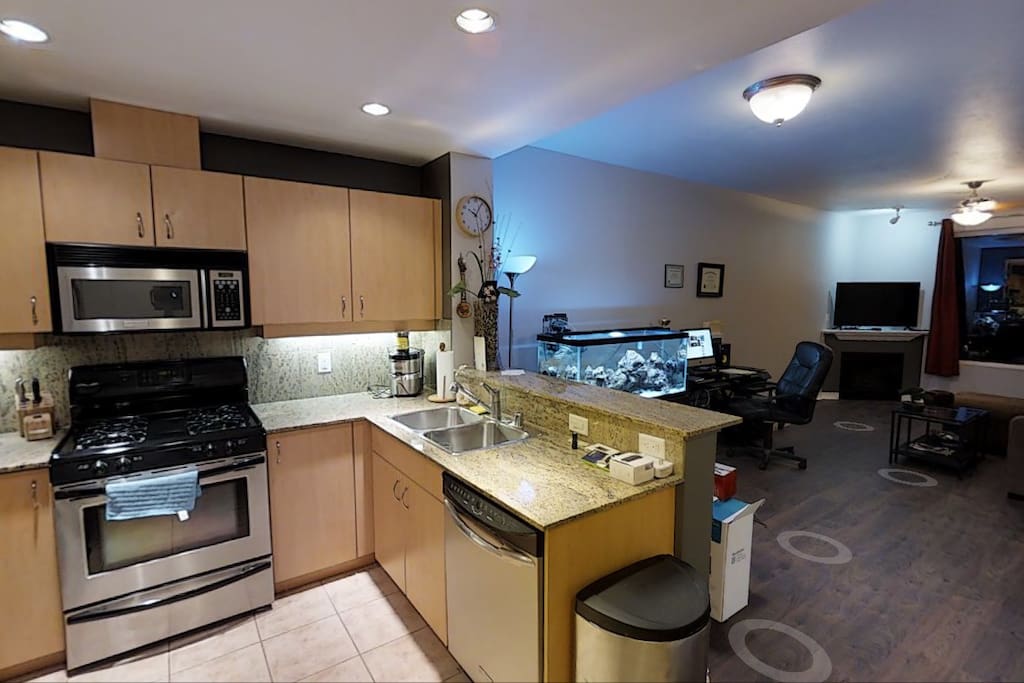 Kitchen with microwave, oven, refrigerator, stove, dishwasher, coffee machine, wine rack, and juicer.