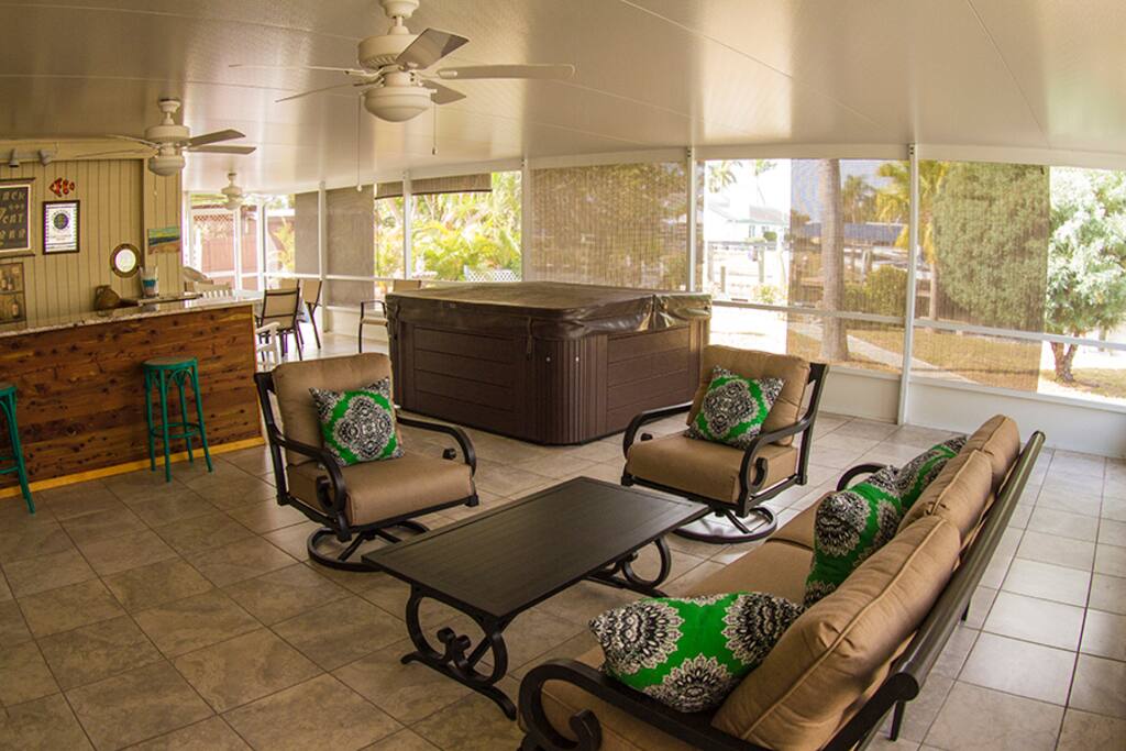 Lanai with hot tub, conversation area with TV, bar, dining area, and gas BBQ