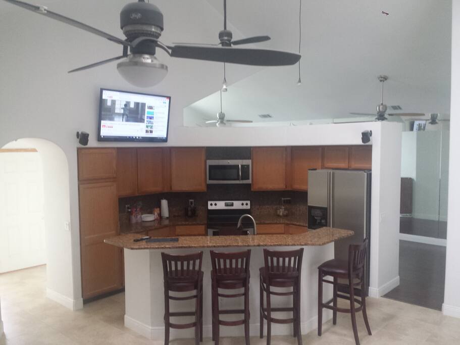 Bar style kitchen with 50" high-mount TV and granite.
