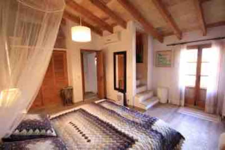 Amplio dormitorio 1, la cama es un somier grande y dos colchones. La escalera va hacia la terraza con vistas al Puig de Maria 
AIr Conditionné.