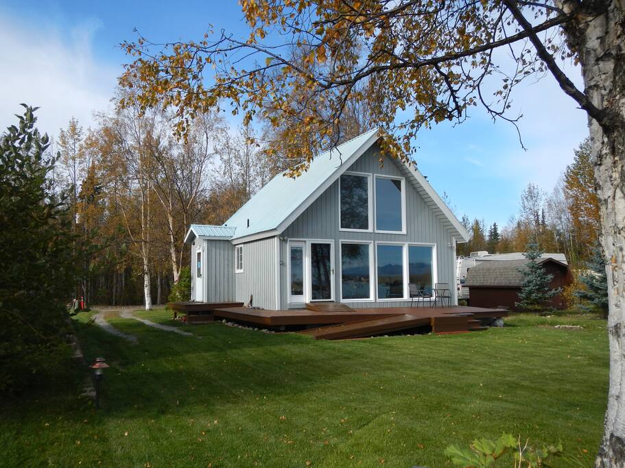 Lake side view of window wall, deck, yard.