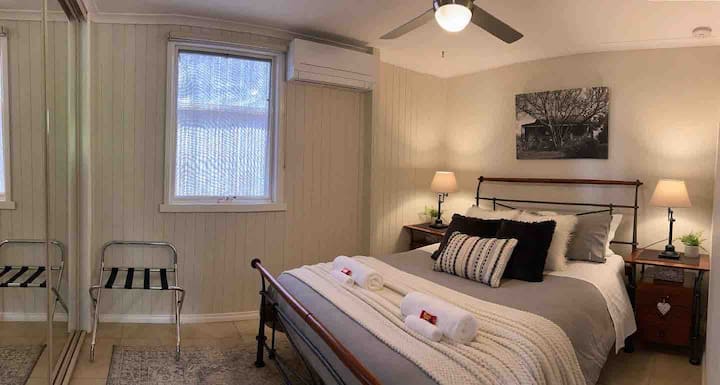 Cosy main bedroom with a comfy queen bed, built-in wardrobe with ample hanging/storage space, and a split system for year-round comfort. Stylish decor, bedside lamps, and a ceiling fan create a relaxing retreat for your stay.