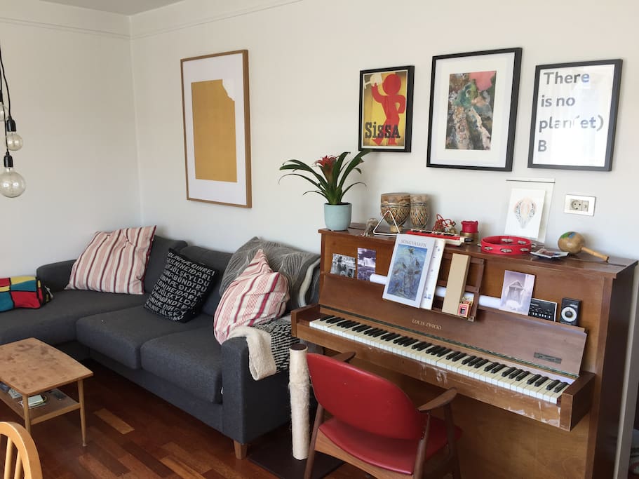 Cozy sofa with blankets, art on the walls and a piano.