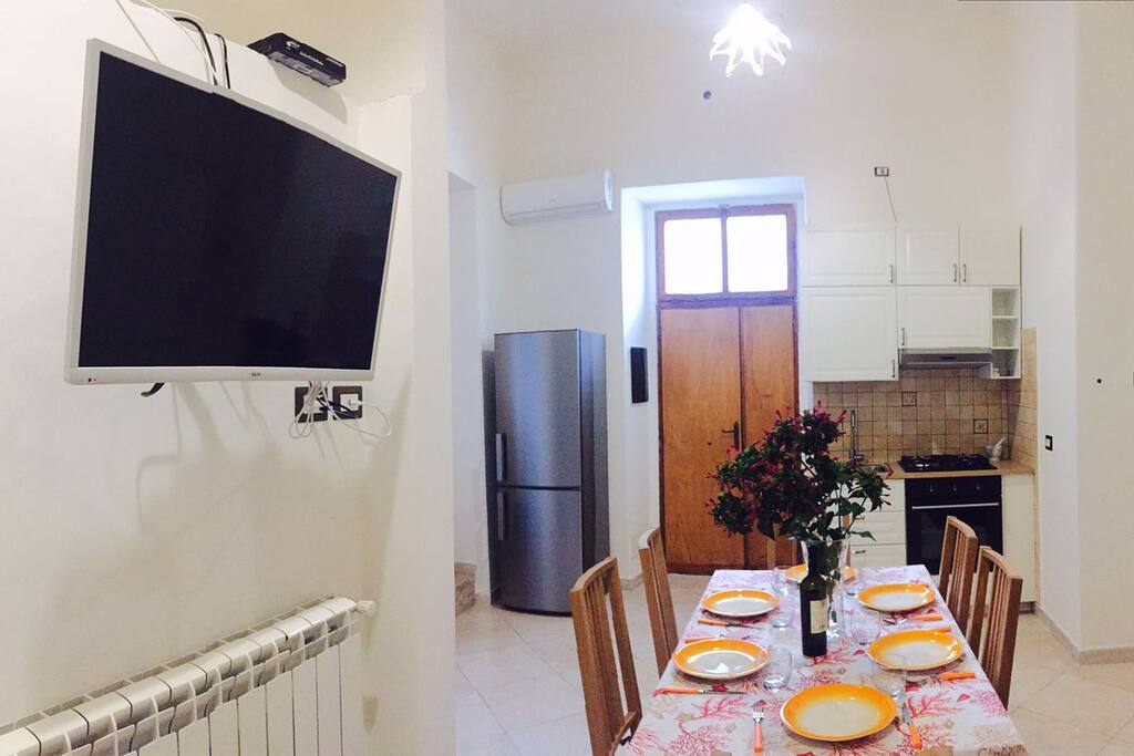 Open space con smart tv e cucina attrezzata.